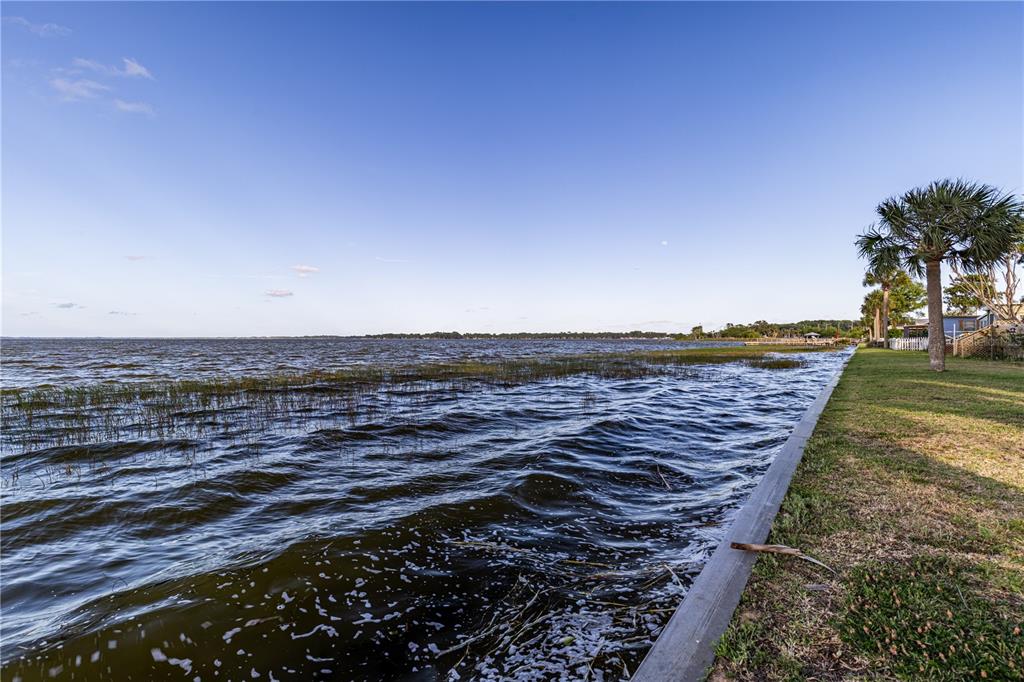 A view of a lake with a grassy shoreline and a concrete retaining wall — 12315 US HIGHWAY 441 UNIT 23, TAVARES, FL