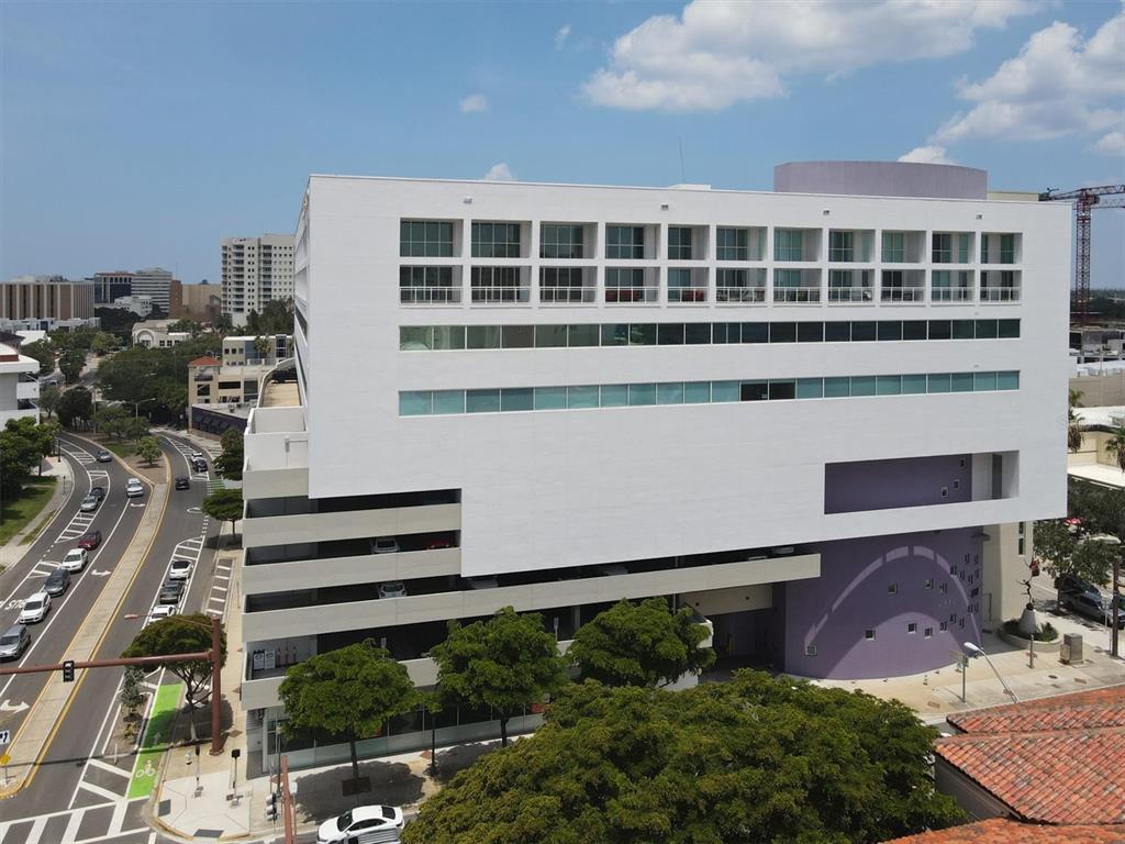 An aerial view of a modern white building with a parking garage and purple accents — 1990 MAIN STREET UNIT 4, SARASOTA, FL