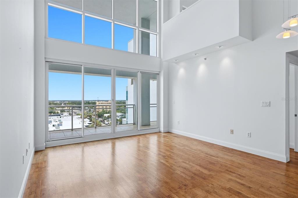 A bright living room with high ceilings, hardwood floors, and a balcony with city views — 1990 MAIN STREET UNIT 4, SARASOTA, FL