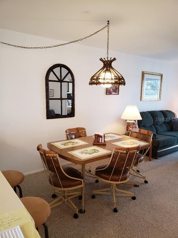A dining area features a wooden table with four chairs under a hanging pendant light — 25225 RAMPART BOULEVARD UNIT 1908, PUNTA GORDA, FL