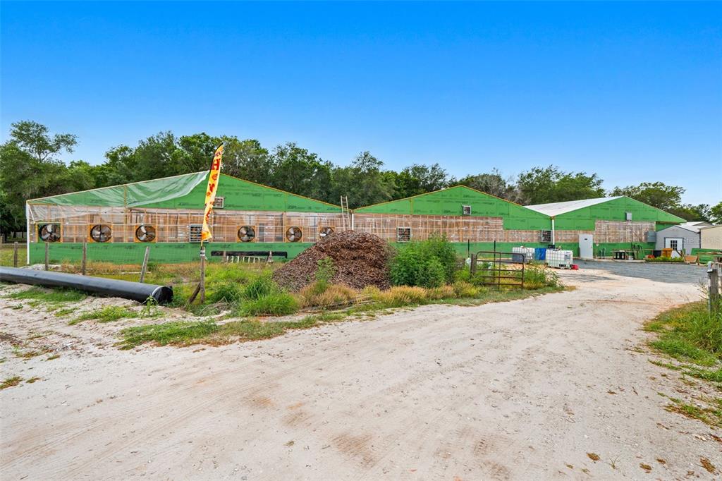 A large, unfinished greenhouse structure sits on a dirt lot with a pile of mulch — 3510 WALK IN WATER ROAD, LAKE WALES, FL