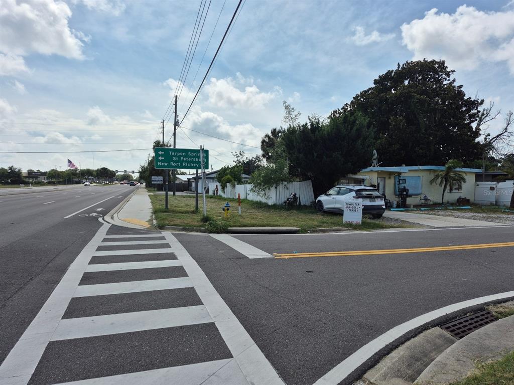 A street-level view shows a crosswalk, a road sign, and a small house with a car — 4007 FLAMINGO DRIVE, NEW PORT RICHEY, FL