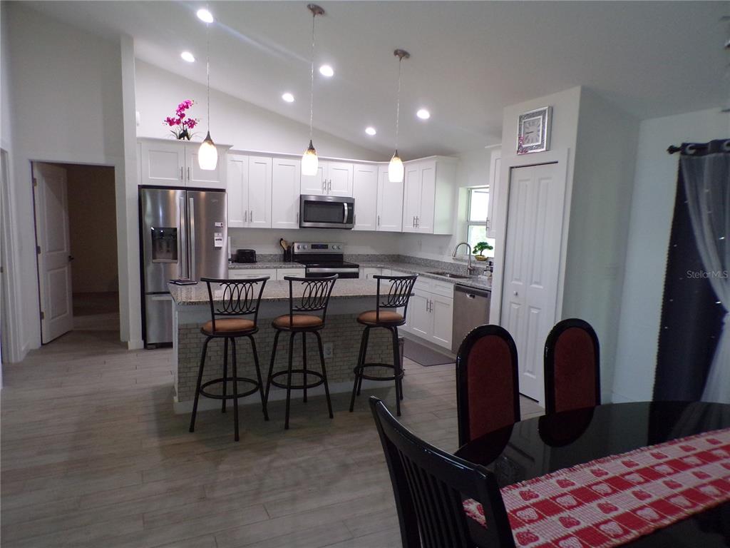 A kitchen with white cabinets, granite countertops, stainless steel appliances, and a breakfast bar — 334 MILLPORT STREET NW, PORT CHARLOTTE, FL