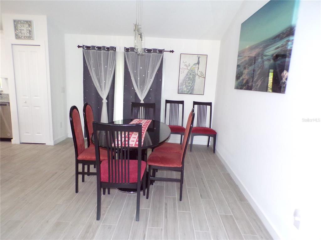 A dining room features a round glass table, six chairs, and light-colored wood-look flooring — 334 MILLPORT STREET NW, PORT CHARLOTTE, FL