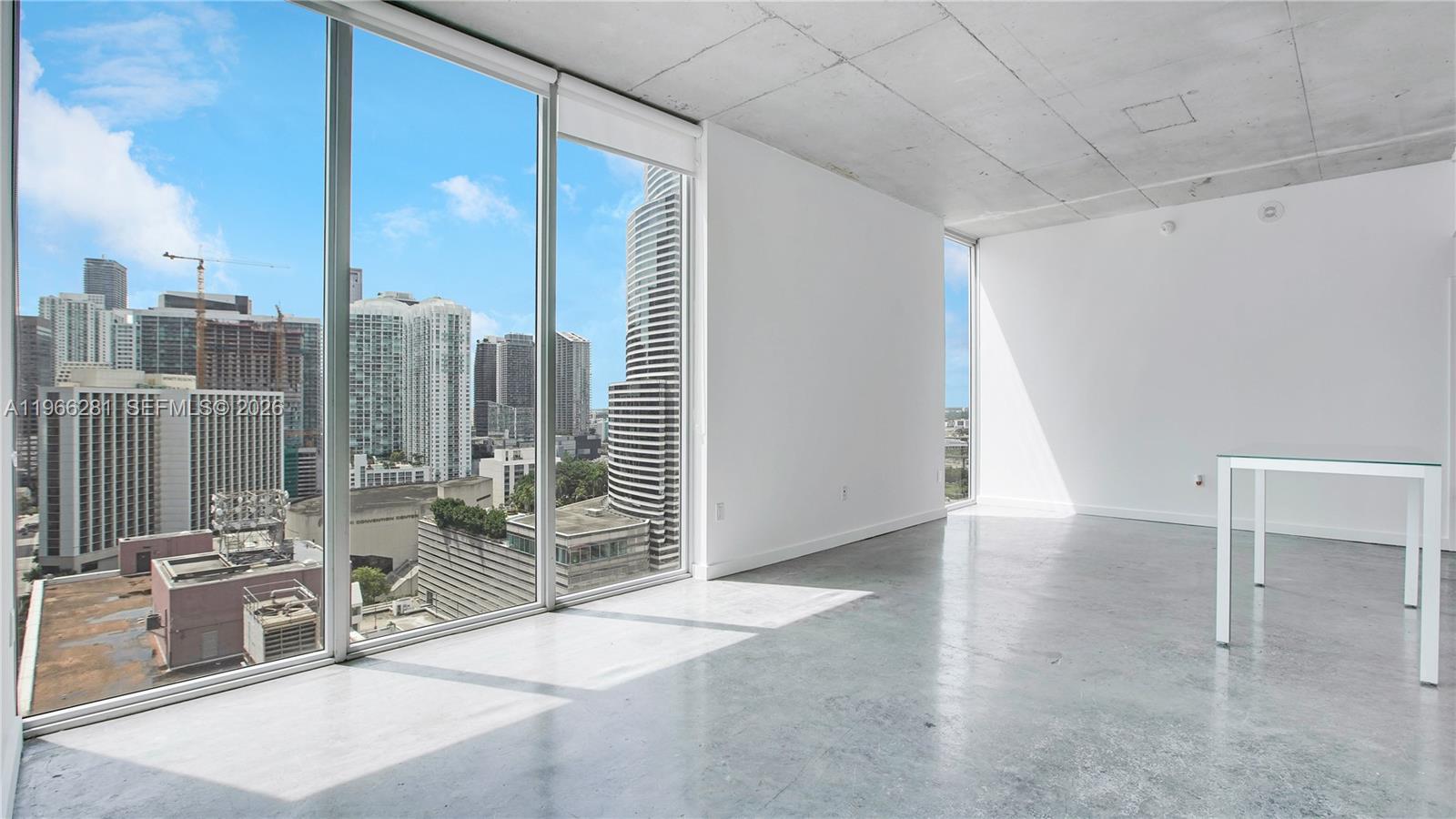 A bright, minimalist room features polished concrete floors, exposed concrete ceilings, and floor-to-ceiling windows — 151 SE 1st St # 2101, Miami FL 33131, MIAMI, FL