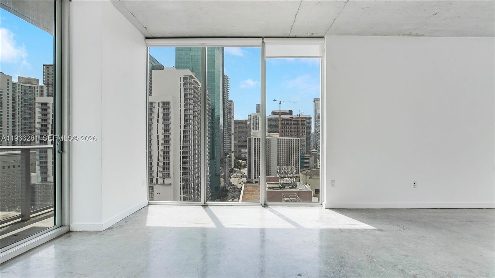 An empty room features concrete floors, white walls, and floor-to-ceiling windows overlooking a city skyline — 151 SE 1st St # 2101, Miami FL 33131, MIAMI, FL