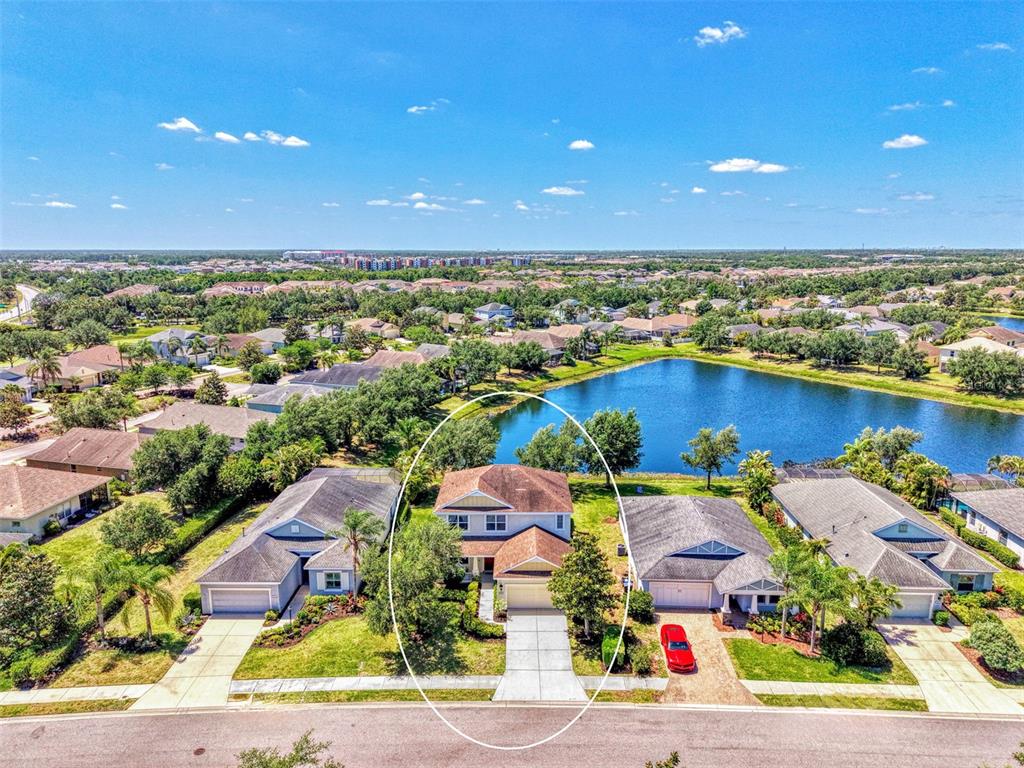 An aerial view shows a two-story house with a driveway and a backyard lake — 5008 MISSION PARK LANE, BRADENTON, FL