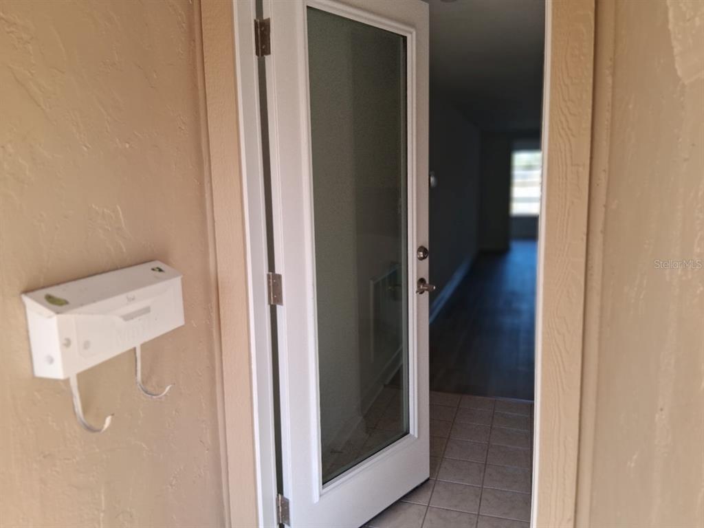 A white exterior door opens into a tiled entryway with a wall-mounted mailbox nearby — 4326 SUMMERSUN DRIVE, NEW PORT RICHEY, FL