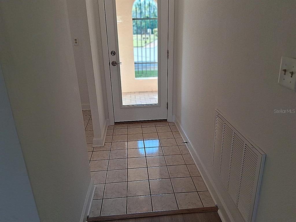 A tiled entryway leads to a glass-paneled door with a view of an outdoor patio — 4326 SUMMERSUN DRIVE, NEW PORT RICHEY, FL