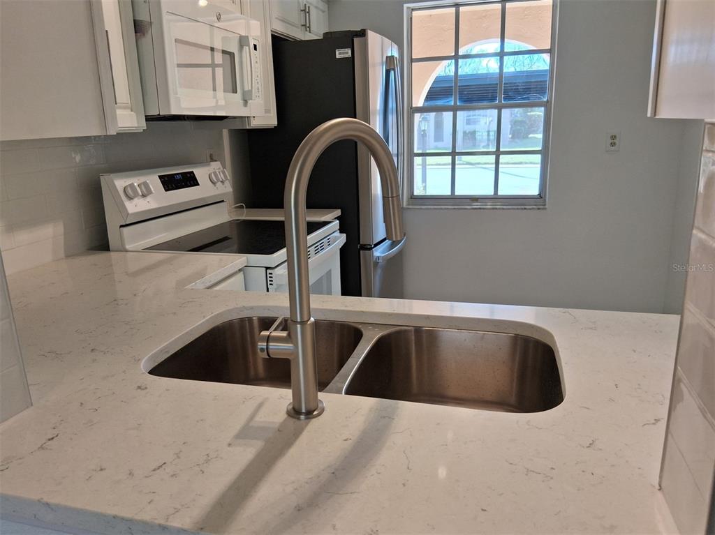 A kitchen features a stainless steel sink, a gooseneck faucet, and white quartz countertops — 4326 SUMMERSUN DRIVE, NEW PORT RICHEY, FL