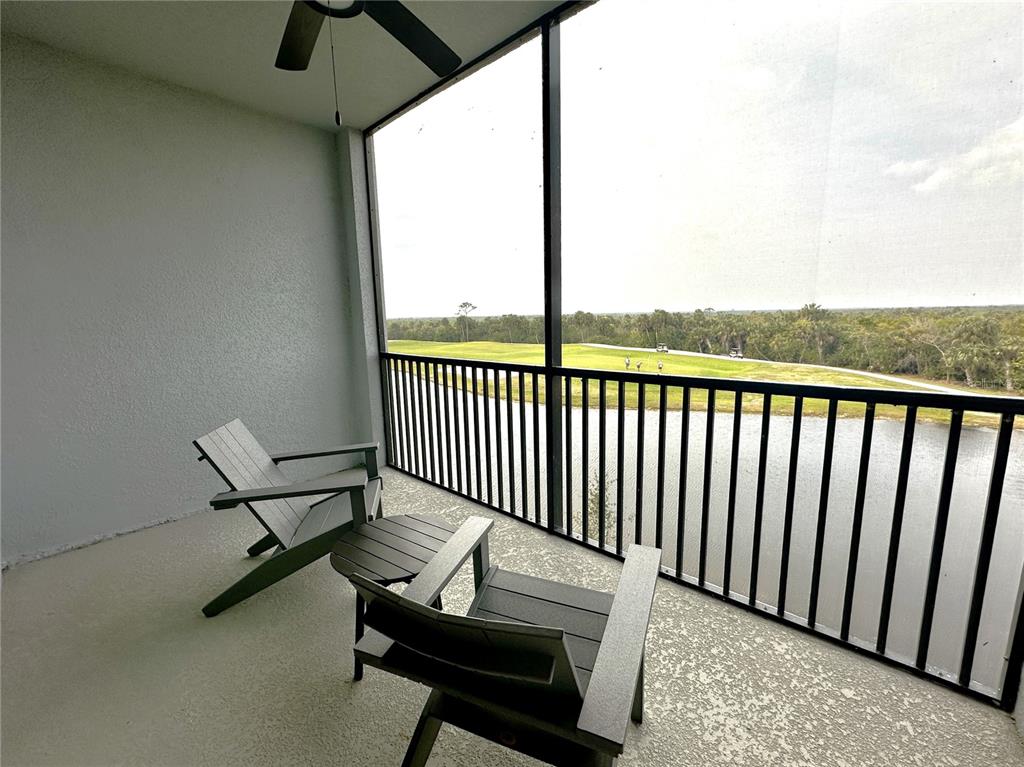 A screened balcony features two chairs, a small table, and a view of a golf course — 14041 HERITAGE LANDING BOULEVARD UNIT 634, PUNTA GORDA, FL