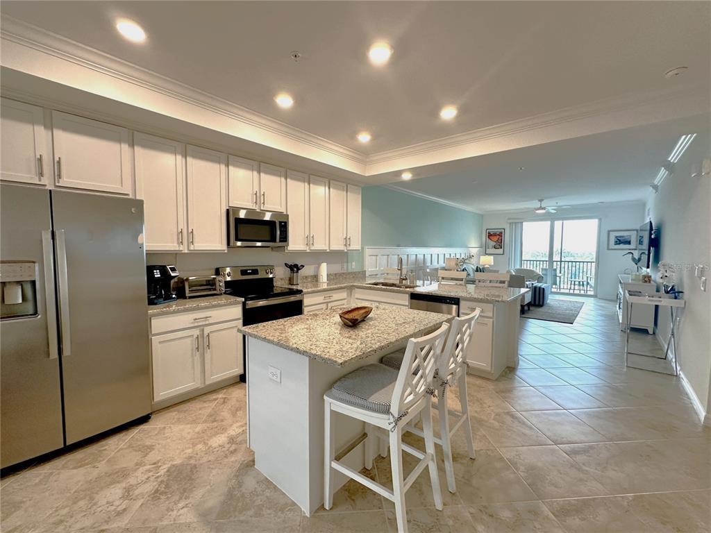 A kitchen with white cabinets, granite countertops, and a center island with two chairs — 14041 HERITAGE LANDING BOULEVARD UNIT 634, PUNTA GORDA, FL