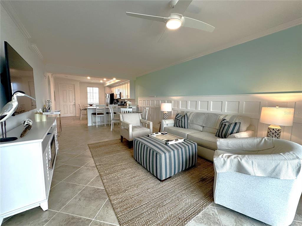 A living room with tile floors, a striped ottoman, and a kitchen in the background — 14041 HERITAGE LANDING BOULEVARD UNIT 634, PUNTA GORDA, FL