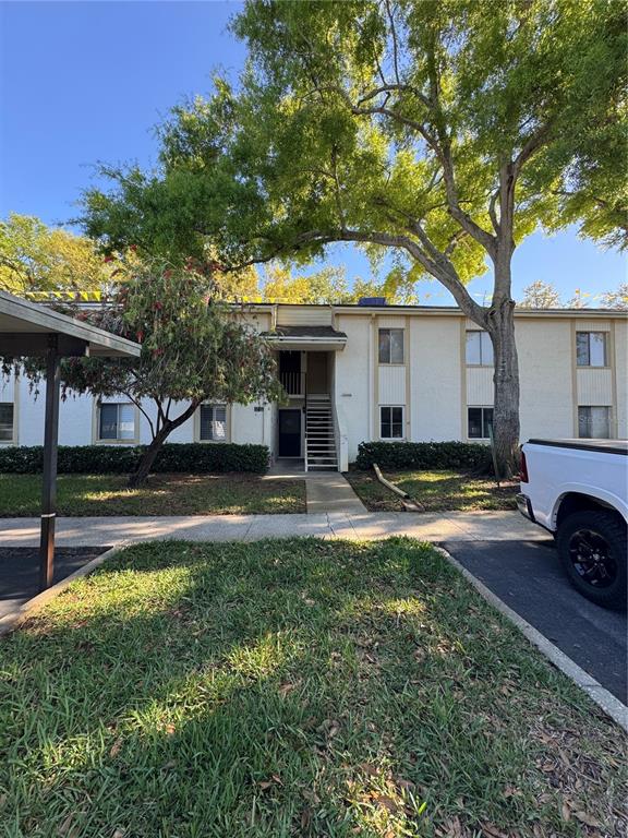 A two-story apartment building with a central staircase, a large tree, and a parked truck — 109 PINE COURT, OLDSMAR, FL