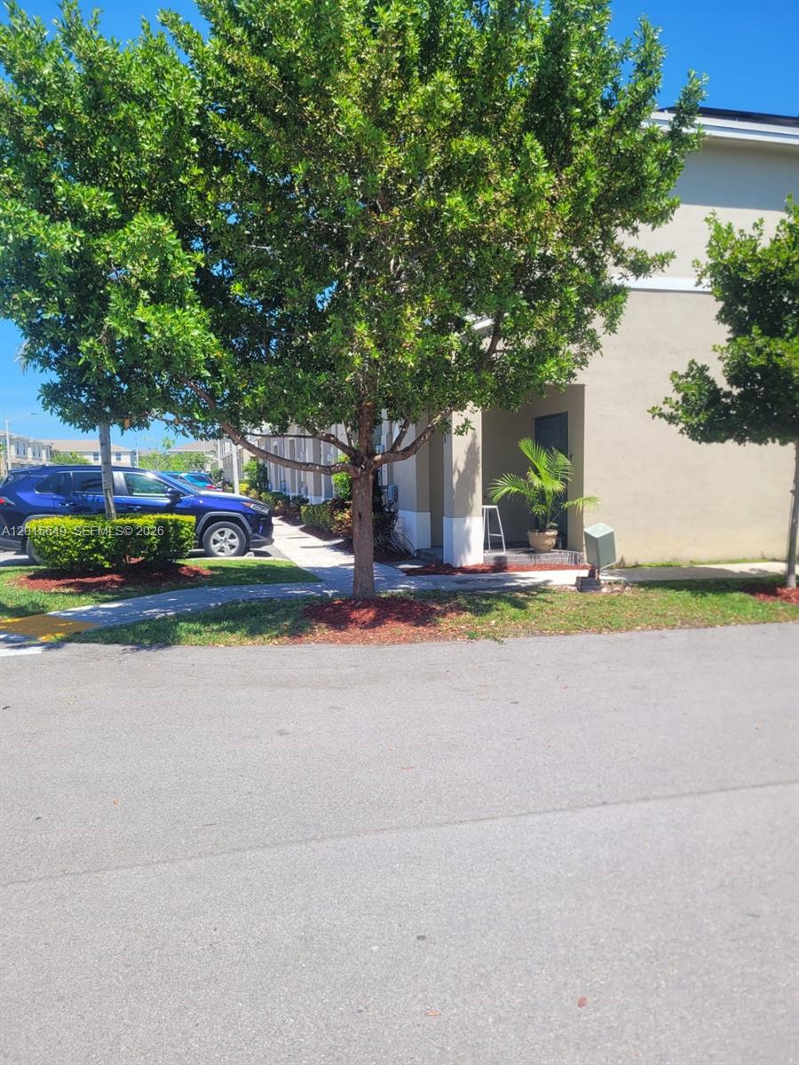 A blue SUV is parked on a street in front of a tan townhouse building — 441 NE 5th St, Florida City FL 33034, FLORIDA CITY, FL
