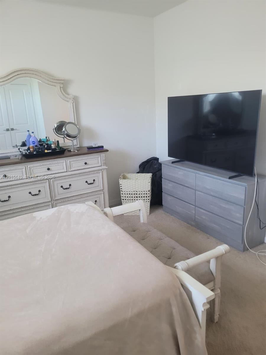 A bedroom features a white dresser with a mirror, a gray dresser with a television, and a bed — 441 NE 5th St, Florida City FL 33034, FLORIDA CITY, FL