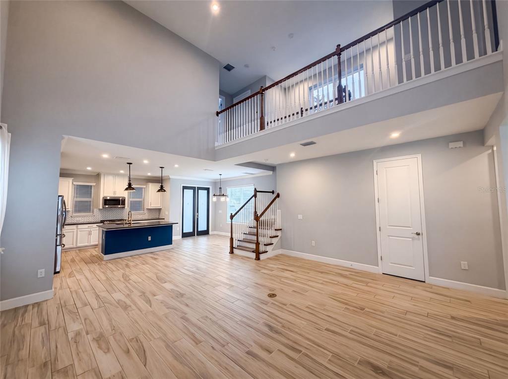 A bright, open-concept living area features a kitchen with a blue island and wooden flooring — 13720 STEVENSON LANE, ODESSA, FL
