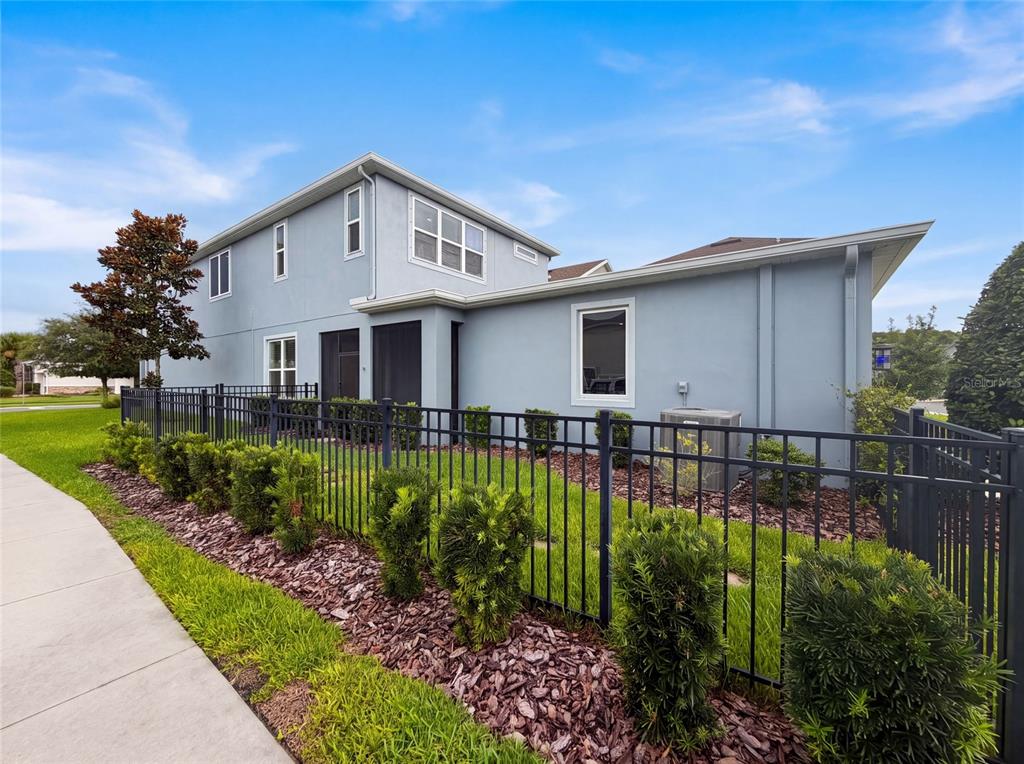 A two-story light blue house with a black metal fence and landscaped yard — 13720 STEVENSON LANE, ODESSA, FL