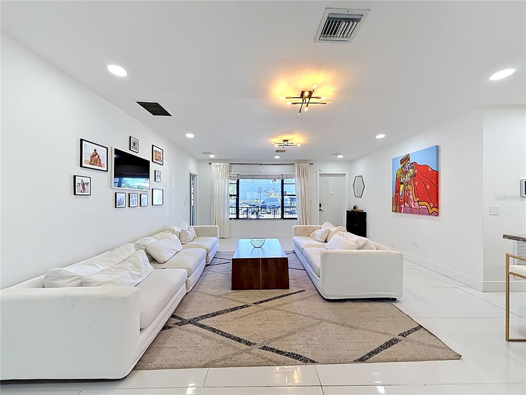 A living room features white sofas, a central coffee table, and a large wall painting — 821 83RD ST, MIAMI BEACH, FL