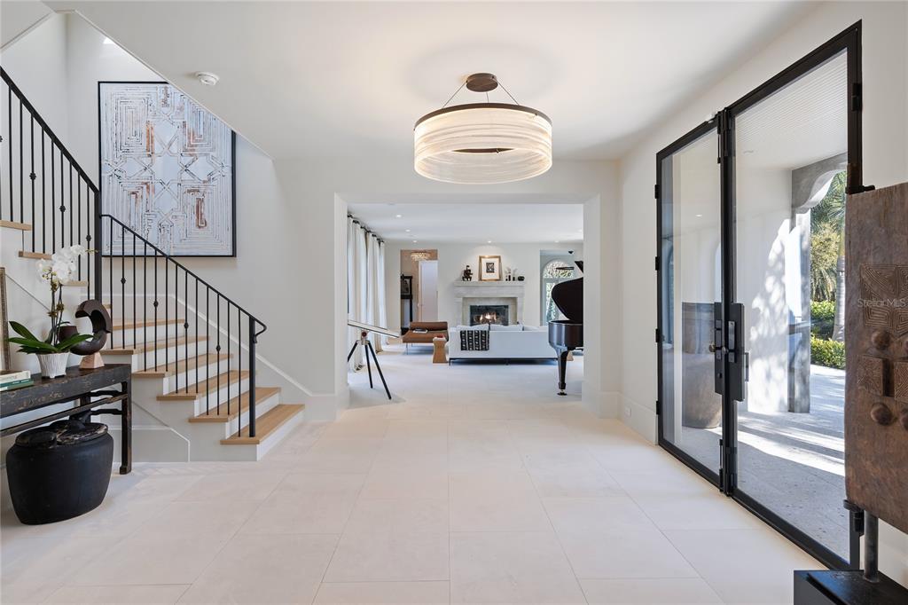 A bright foyer features light tile floors, a staircase with black railings, and a grand piano — 416 BRIGHTWATERS BOULEVARD NE, ST PETERSBURG, FL