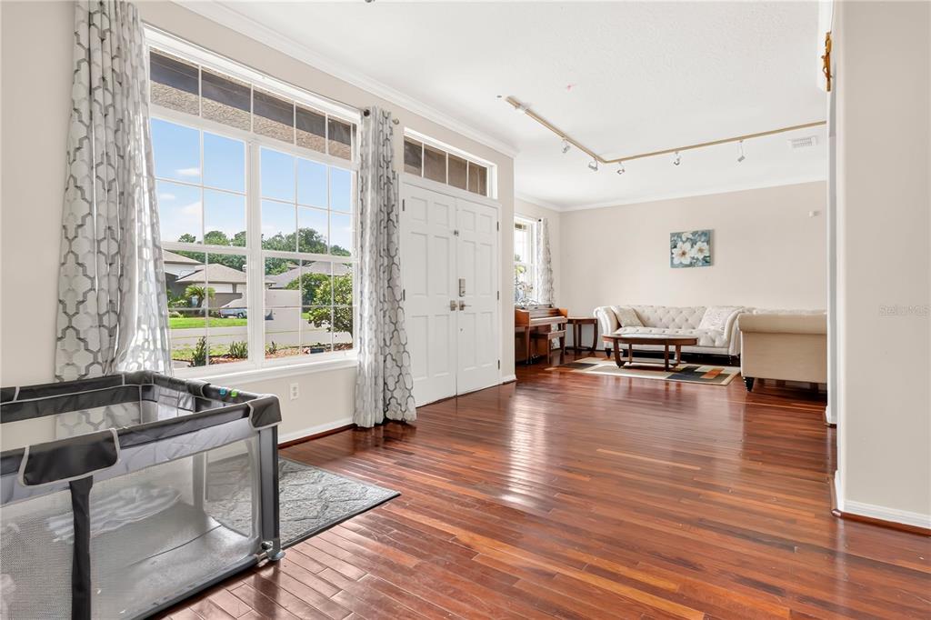 A living room with hardwood floors, a large window, and a white front door — 8044 CANYON LAKE CIRCLE, ORLANDO, FL