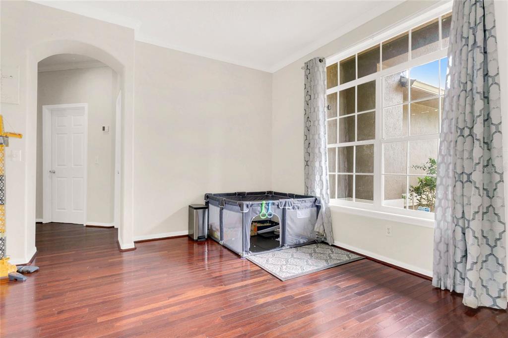 A room with hardwood floors, a large window with patterned curtains, and a playpen — 8044 CANYON LAKE CIRCLE, ORLANDO, FL