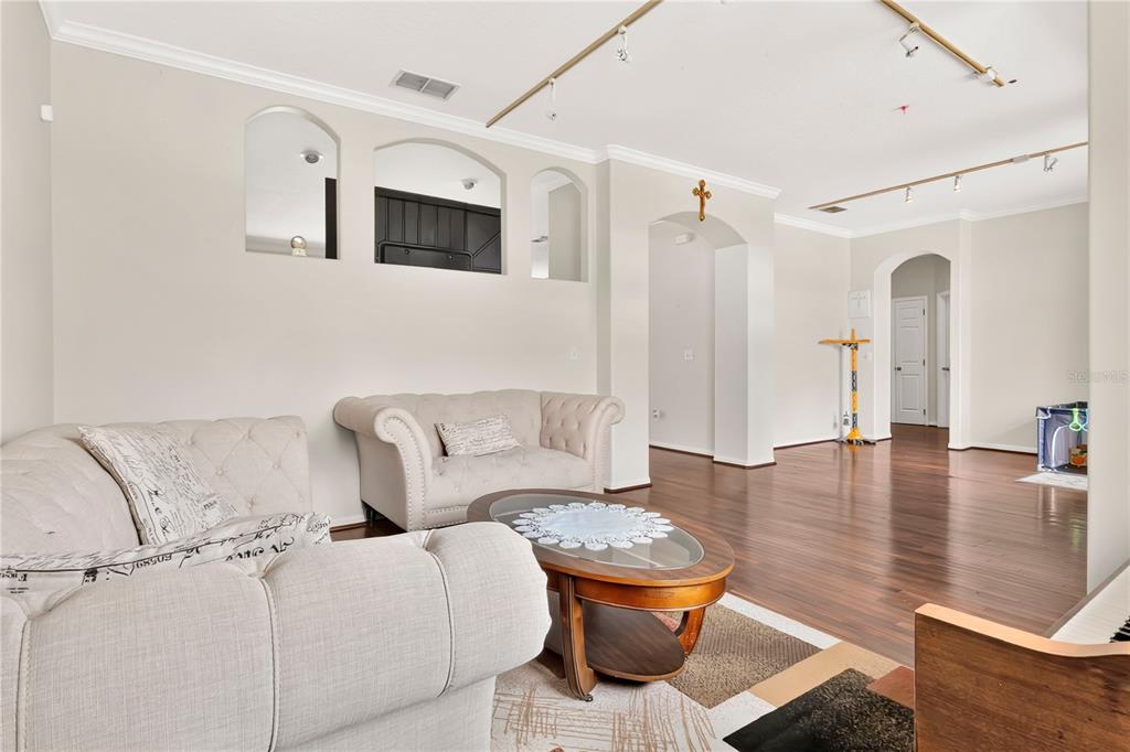 A living room features light-colored tufted sofas, a wooden coffee table, and arched wall niches — 8044 CANYON LAKE CIRCLE, ORLANDO, FL