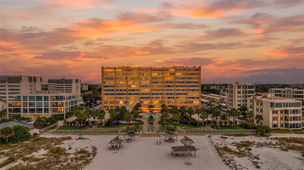An aerial view of a multi-story apartment building on a sandy beach at sunset — 6140 MIDNIGHT PASS ROAD UNIT 904, SARASOTA, FL