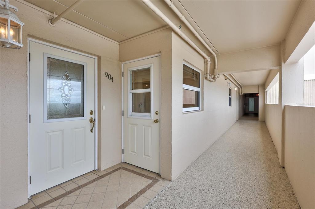 An exterior hallway features two white doors, one marked 904, with tiled and textured flooring — 6140 MIDNIGHT PASS ROAD UNIT 904, SARASOTA, FL