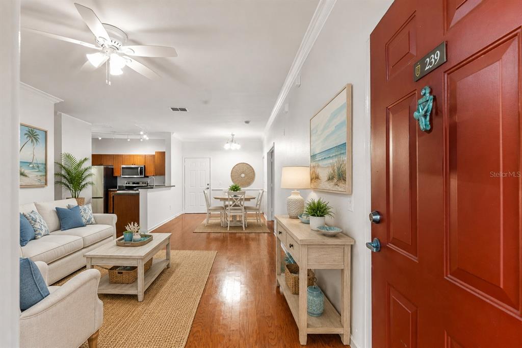An interior view shows a living room with hardwood floors, a dining area, and a kitchen — 2250 PORTOFINO PLACE UNIT 239, PALM HARBOR, FL