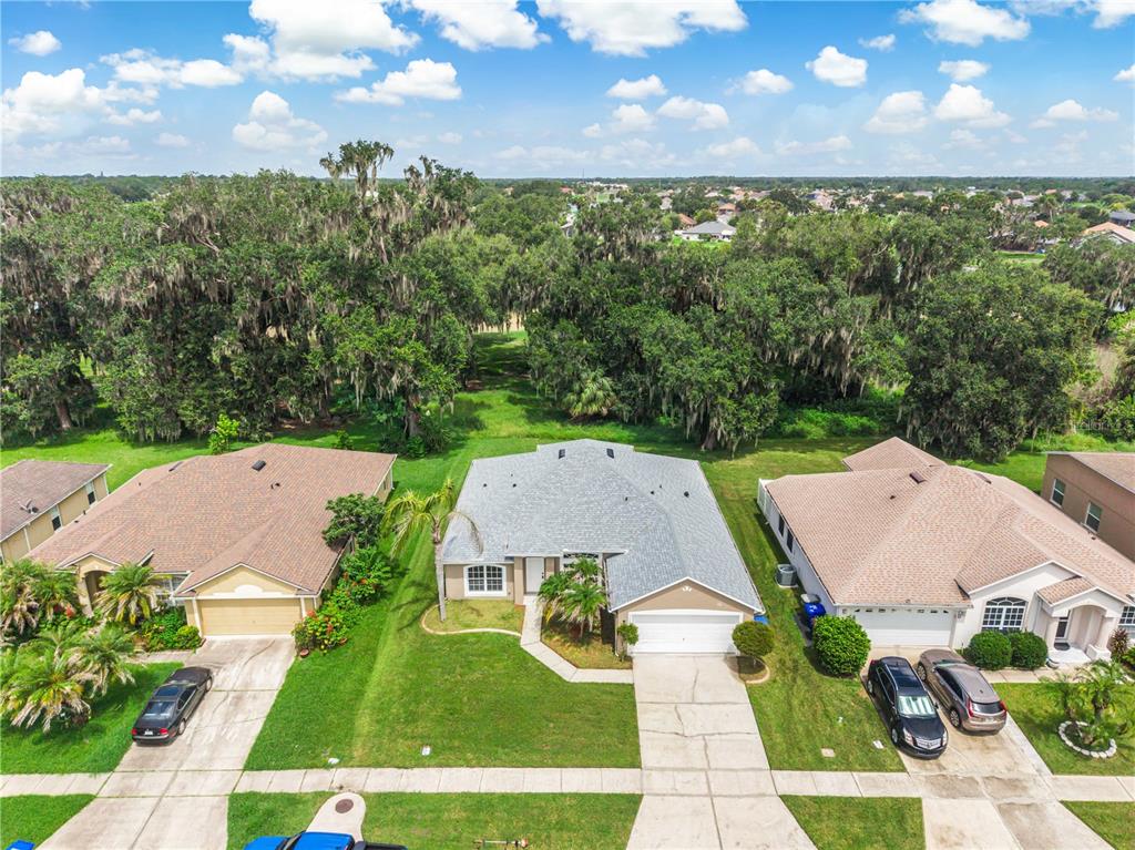 An aerial view of a single-story suburban house with a gray roof and concrete driveway — 2106 THE OAKS BOULEVARD, KISSIMMEE, FL