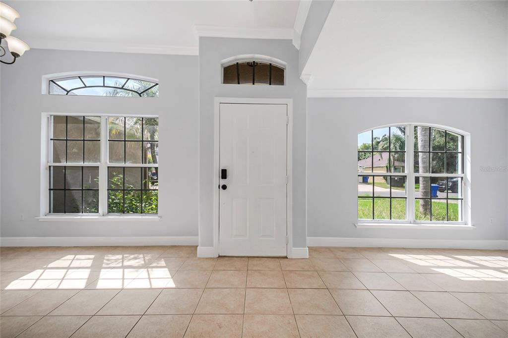 An entryway with light tile floors, a white front door, and arched windows — 2106 THE OAKS BOULEVARD, KISSIMMEE, FL