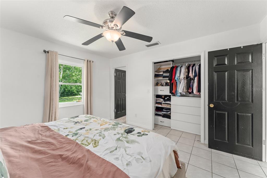 A bedroom with white walls, tile flooring, a ceiling fan, and a walk-in closet — 429 VIRGINIA AVENUE, ST CLOUD, FL