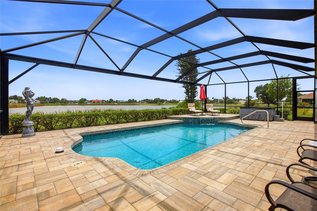 A screened-in pool area features a paved deck, a water feature, and a lake view — 7100 SAN CASA DRIVE, ENGLEWOOD, FL