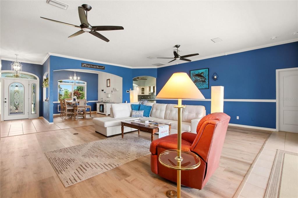 A living room with blue walls, a white sectional sofa, and a red armchair — 7100 SAN CASA DRIVE, ENGLEWOOD, FL
