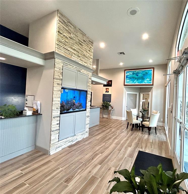 A lobby features a stone-clad fireplace with a built-in aquarium, wood-look flooring, and seating area — 1203 W MARION AVENUE, PUNTA GORDA, FL
