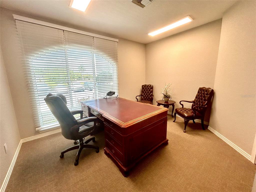 A home office features a large wooden desk, three leather chairs, and a window with blinds — 1203 W MARION AVENUE, PUNTA GORDA, FL