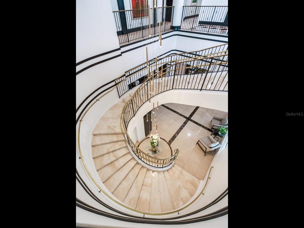 A curved stone staircase with a metal railing overlooks a tiled foyer with seating — 3507 BAYSHORE BOULEVARD UNIT 2001, TAMPA, FL