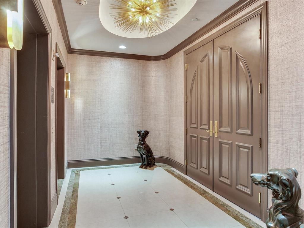 A formal entryway features textured wallpaper, a starburst chandelier, double doors, and two dog statues — 3507 BAYSHORE BOULEVARD UNIT 2001, TAMPA, FL