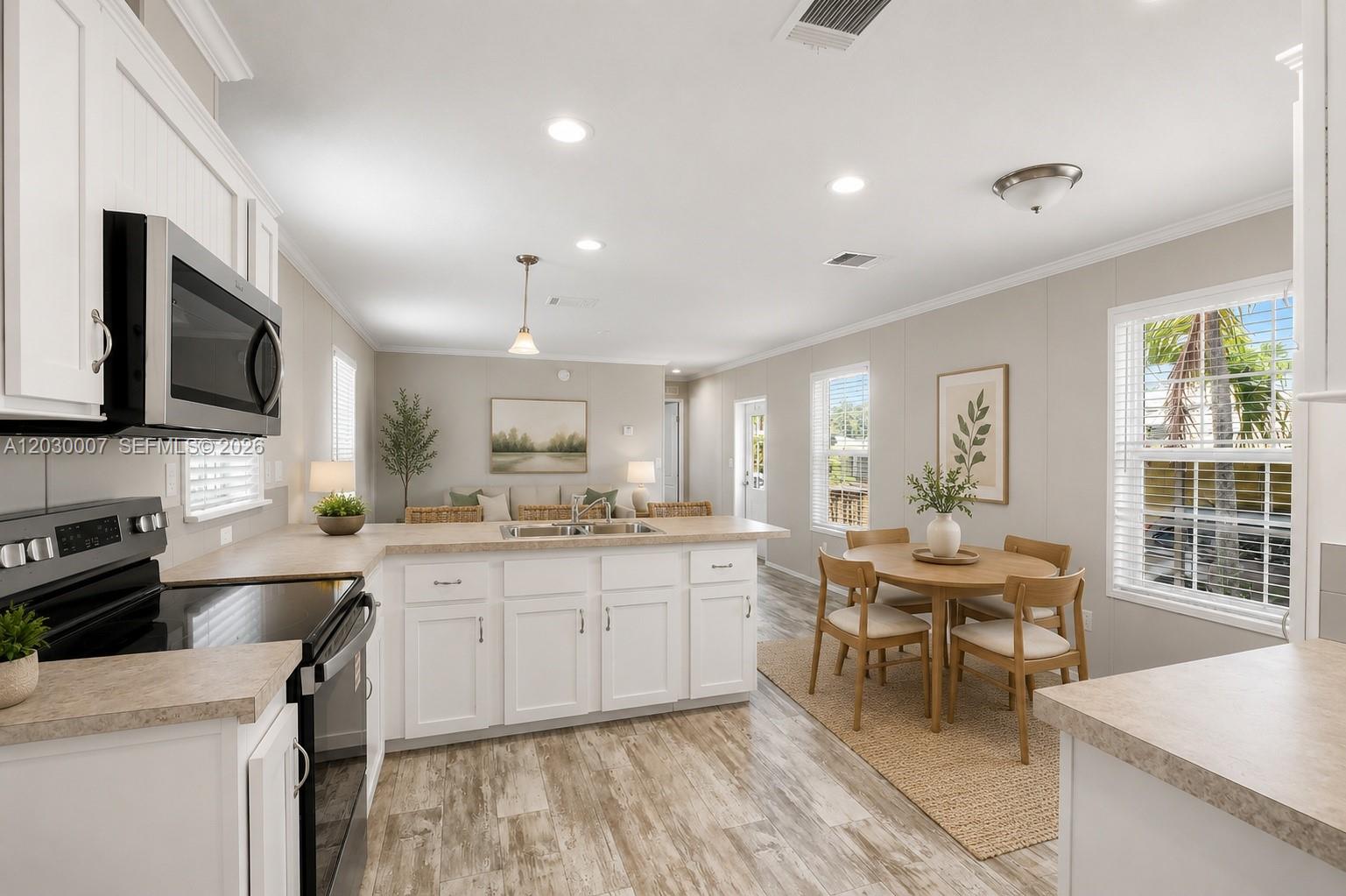 A kitchen features white cabinets, a central island with a sink, and wood-look flooring — 5530 SW 32nd Ter, Dania Beach FL 33312, DANIA BEACH, FL