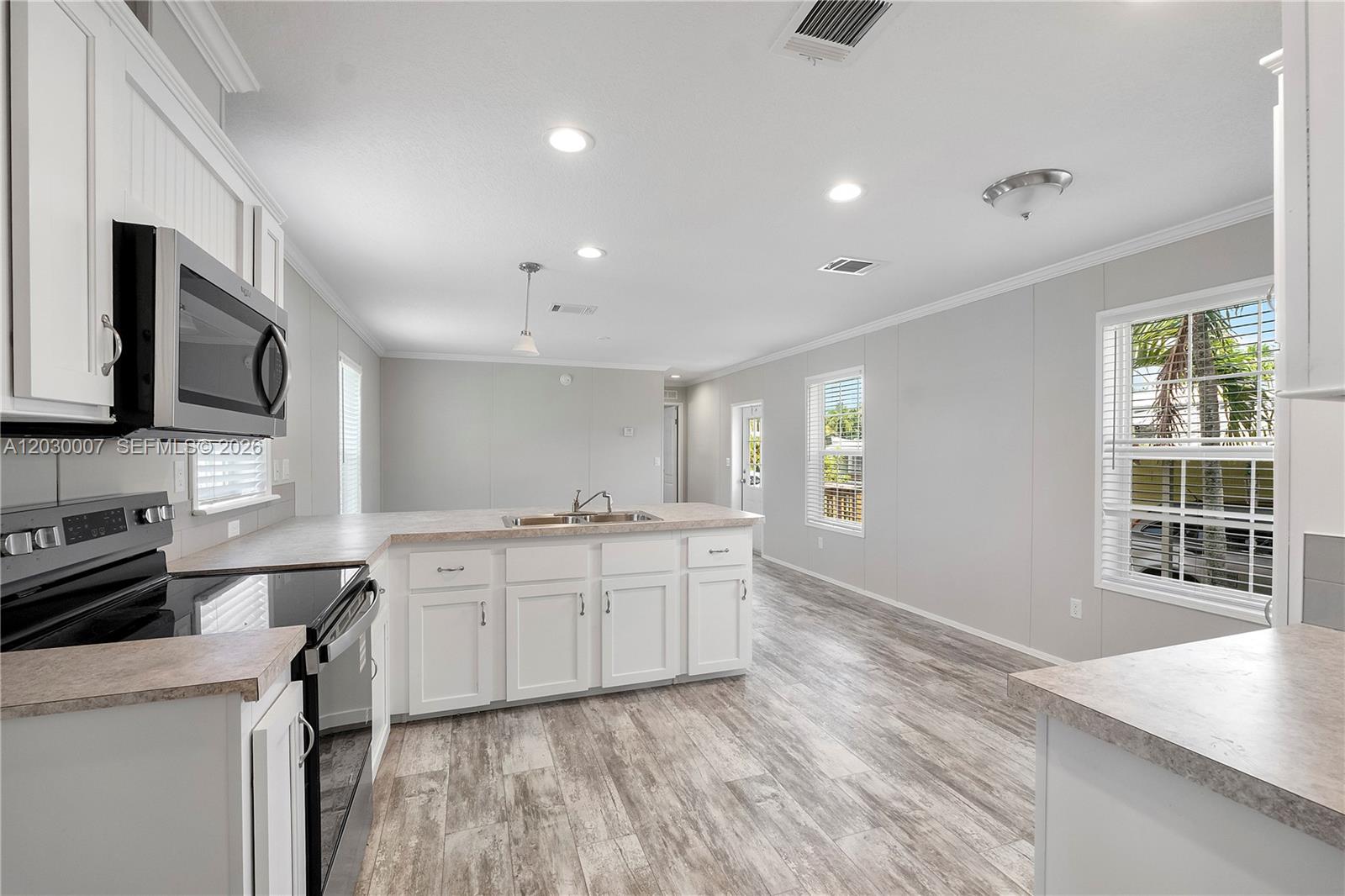 A kitchen with white cabinets, laminate countertops, and wood-look flooring in an open floor plan — 5530 SW 32nd Ter, Dania Beach FL 33312, DANIA BEACH, FL