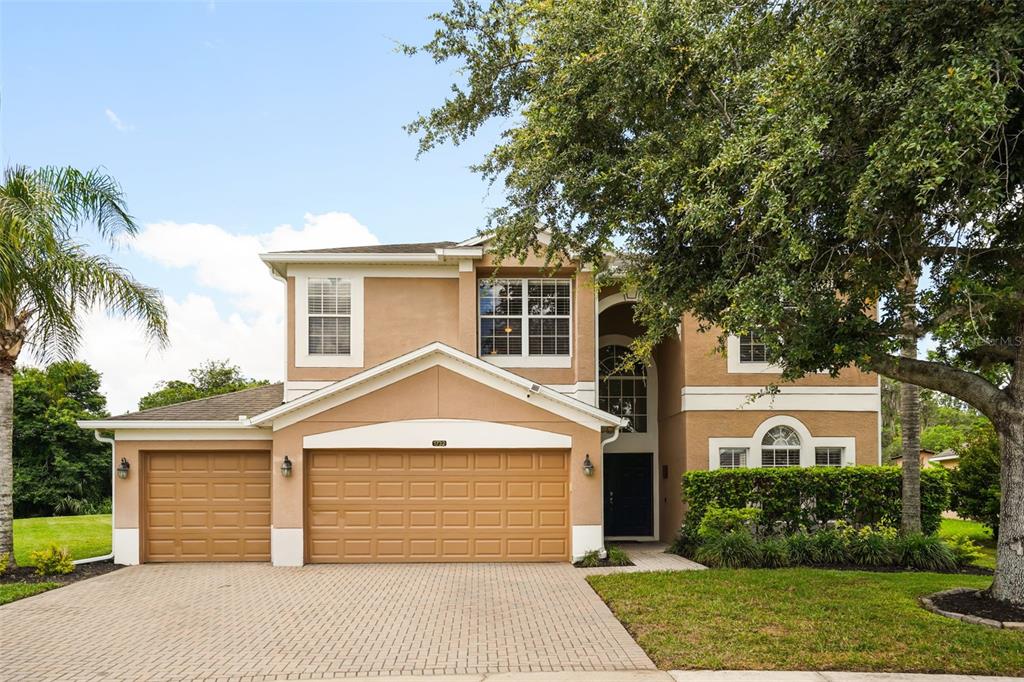 A two-story tan house with a three-car garage and a paved driveway — 1732 BILLIE LYNN POINT, SANFORD, FL