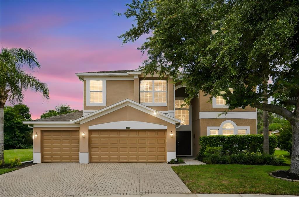 A two-story suburban house with a tan stucco exterior, a three-car garage, and a paved driveway — 1732 BILLIE LYNN POINT, SANFORD, FL