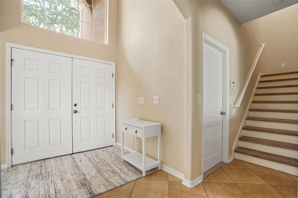 An entryway features a double front door, a white console table, and a wooden staircase — 1732 BILLIE LYNN POINT, SANFORD, FL