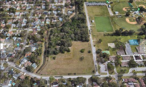 An aerial view shows a vacant, partially wooded lot bordered by residential streets and a park — 1 ARMAND DRIVE, TAMPA, FL