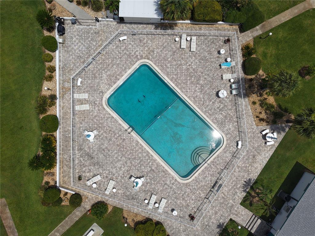 An aerial view shows a rectangular swimming pool surrounded by a paved deck and landscaping — 1600 W LAKE PARKER DRIVE UNIT B23, LAKELAND, FL