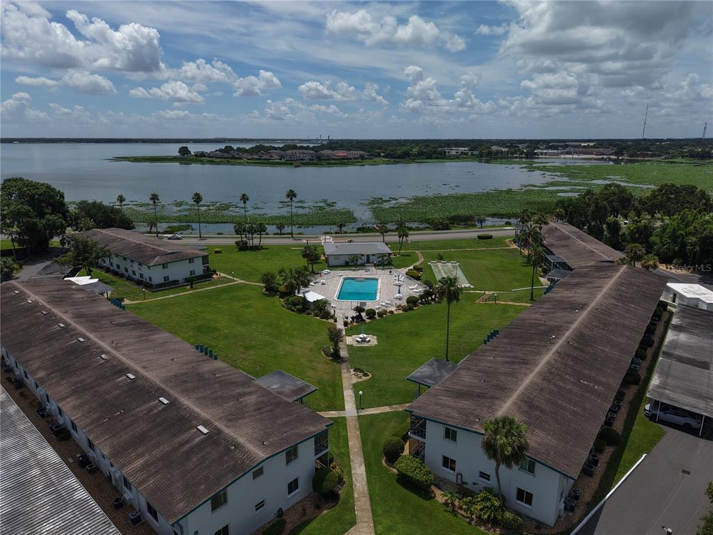 An aerial view shows apartment buildings surrounding a central courtyard with a swimming pool — 1600 W LAKE PARKER DRIVE UNIT B23, LAKELAND, FL