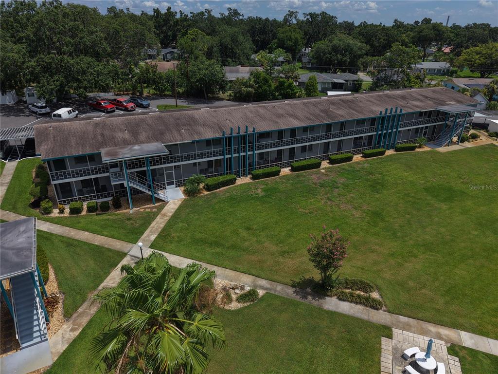 An aerial view shows a long, two-story apartment building with exterior walkways and a large lawn — 1600 W LAKE PARKER DRIVE UNIT B23, LAKELAND, FL