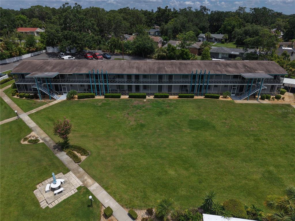 An aerial view shows a long, two-story apartment building with exterior walkways and a lawn — 1600 W LAKE PARKER DRIVE UNIT B23, LAKELAND, FL