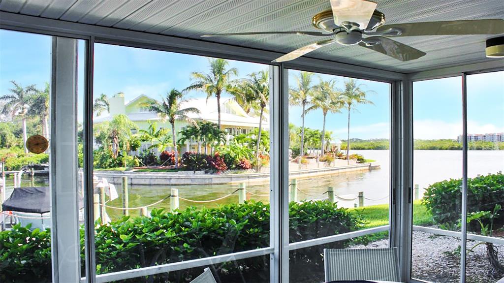A screened-in porch overlooks a canal with palm trees and a house across the water — 1351 SIESTA BAYSIDE DRIVE UNIT 1351-D, SARASOTA, FL